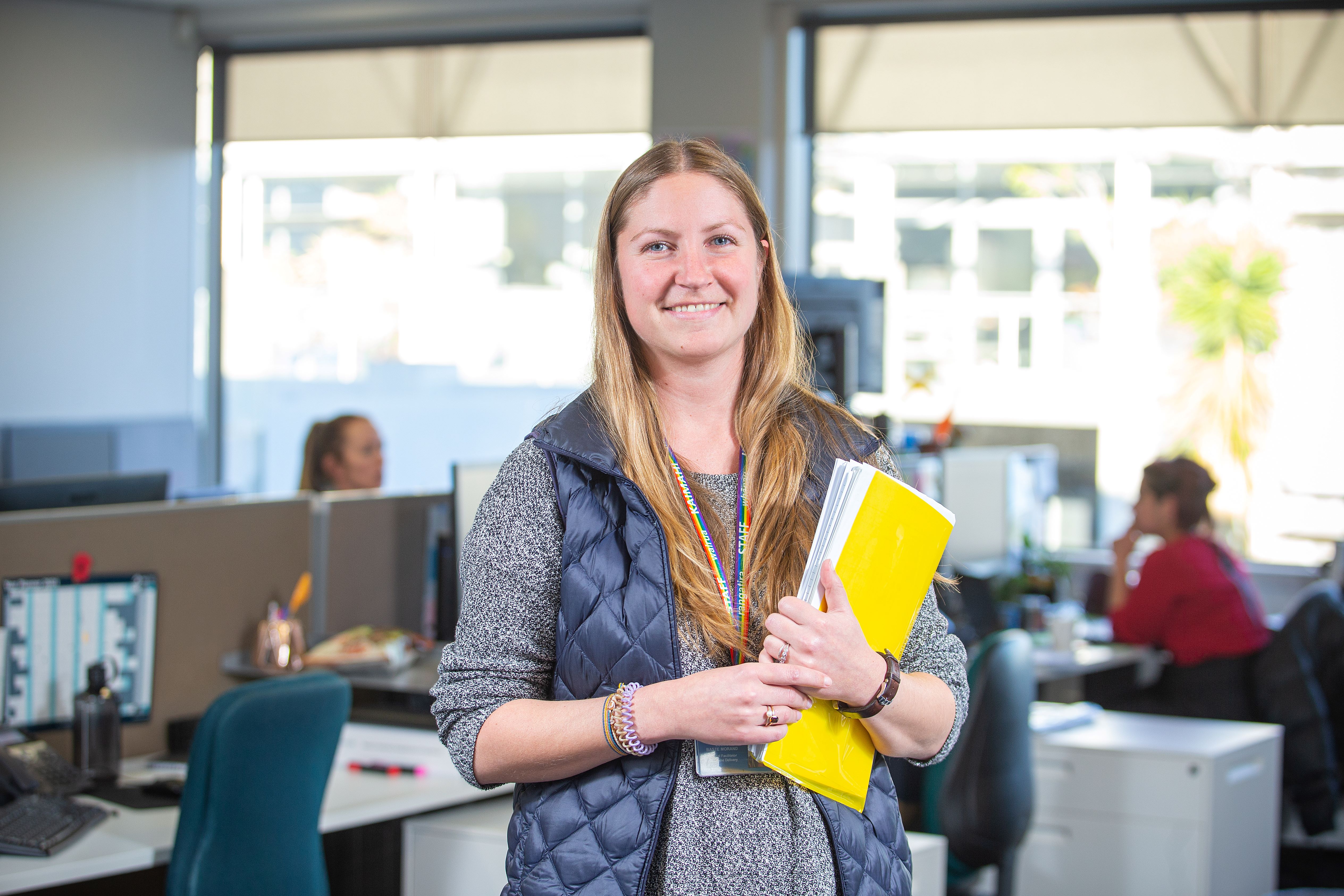 Staff member stands in Community Corrections centre holding a yellow folder